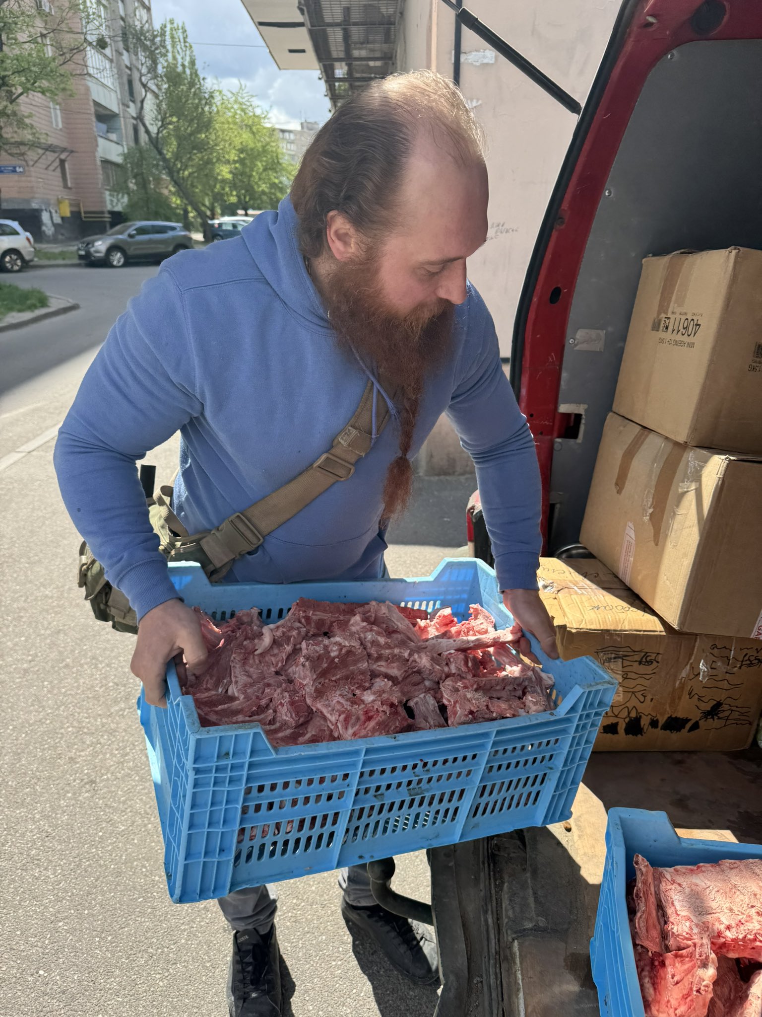 A man holding a crate of raw animal feed and loading it into a van